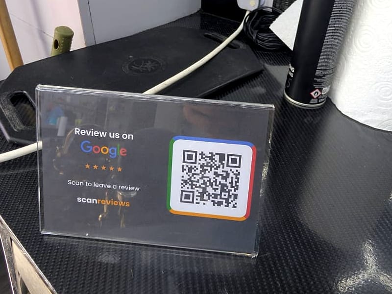 A ScanReviews Google review card on a hair salon styling station beside the mirror